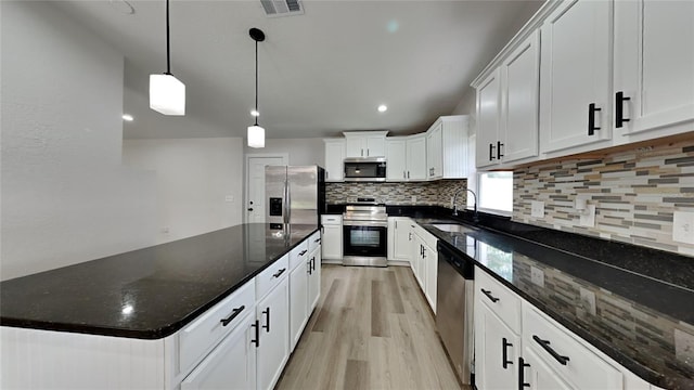 kitchen featuring white cabinets, sink, appliances with stainless steel finishes, decorative light fixtures, and light hardwood / wood-style floors