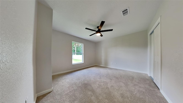 carpeted spare room featuring ceiling fan and a textured ceiling