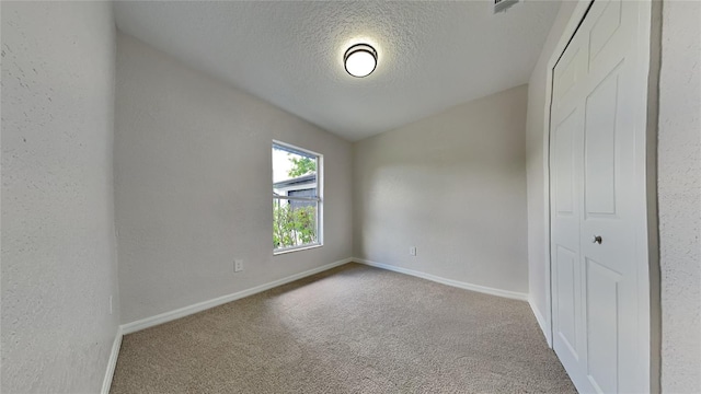 carpeted spare room with a textured ceiling and lofted ceiling