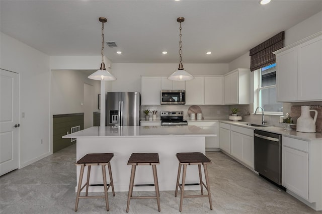 kitchen with pendant lighting, stainless steel appliances, a kitchen island, and white cabinetry