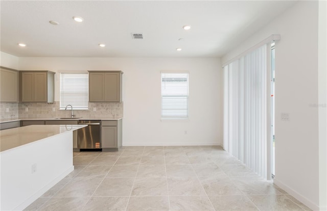 kitchen featuring a sink, stainless steel dishwasher, backsplash, and gray cabinetry