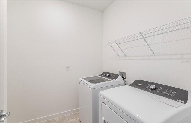 laundry room with laundry area, light tile patterned floors, baseboards, and separate washer and dryer