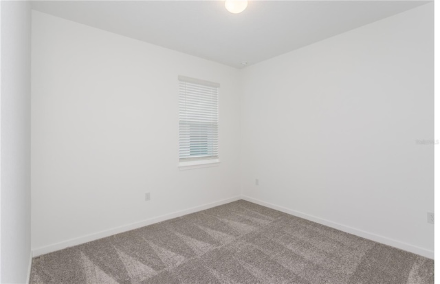 empty room featuring carpet and baseboards