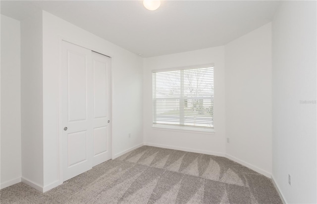 unfurnished bedroom with a closet, carpet flooring, and baseboards