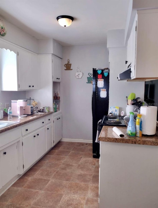 kitchen with white cabinets, black fridge, and exhaust hood