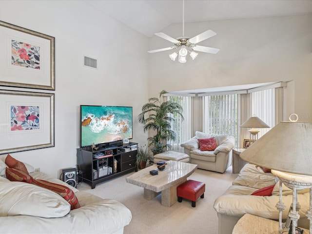 carpeted living room with ceiling fan and high vaulted ceiling