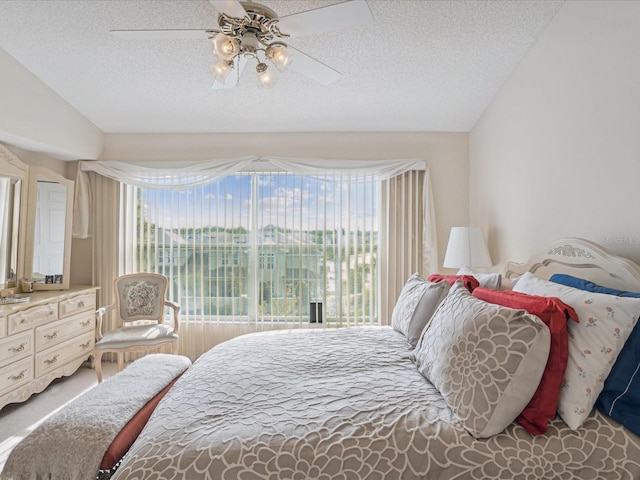 bedroom featuring ceiling fan, carpet floors, a textured ceiling, and lofted ceiling