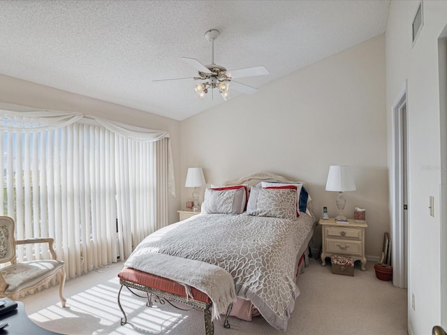 carpeted bedroom featuring ceiling fan, lofted ceiling, and a textured ceiling