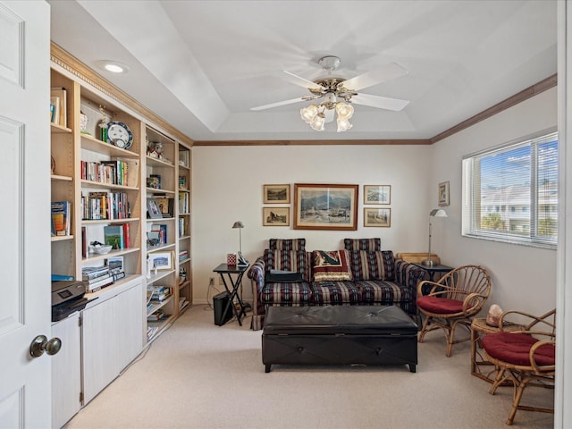 carpeted living room with a tray ceiling, ceiling fan, and crown molding