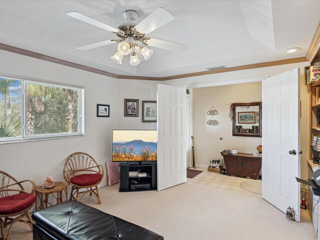 living area featuring carpet flooring, ceiling fan, and crown molding