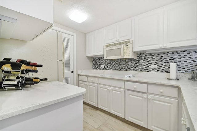 kitchen with backsplash, white cabinetry, light stone counters, and white appliances