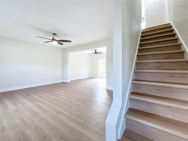 stairway with hardwood / wood-style flooring and ceiling fan