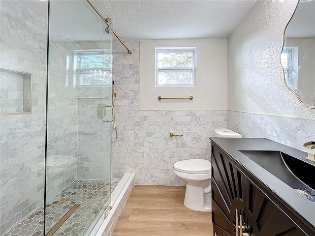 bathroom with vanity, toilet, a textured ceiling, tile walls, and wood-type flooring