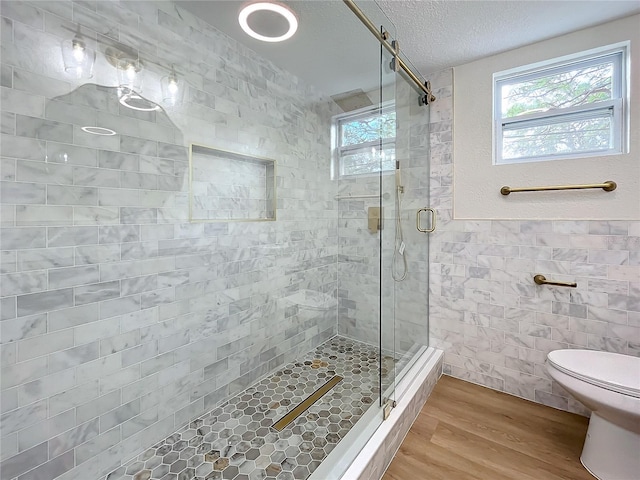 bathroom featuring hardwood / wood-style floors, toilet, a textured ceiling, tile walls, and walk in shower