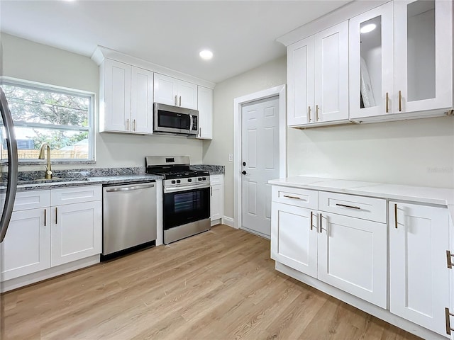 kitchen with white cabinets, appliances with stainless steel finishes, and light hardwood / wood-style flooring