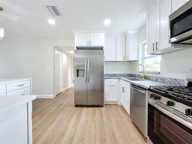 kitchen featuring white cabinets, appliances with stainless steel finishes, light wood-type flooring, and sink