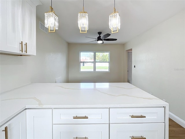 kitchen with light stone counters, ceiling fan, hardwood / wood-style flooring, white cabinetry, and hanging light fixtures