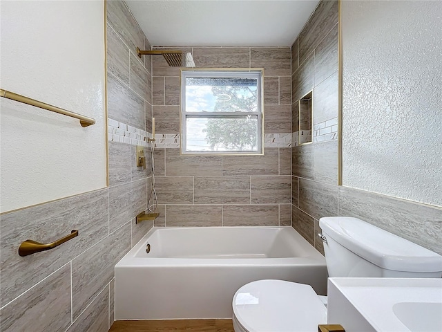 full bathroom with vanity, tiled shower / bath, tile walls, and toilet