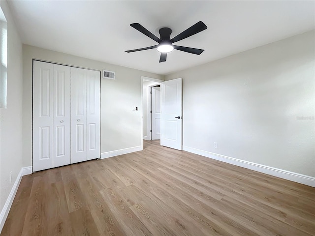 unfurnished bedroom with ceiling fan, light wood-type flooring, and a closet