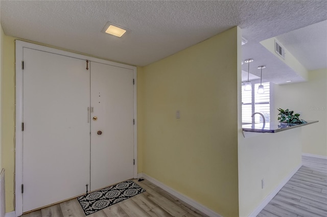 foyer with light hardwood / wood-style floors and a textured ceiling