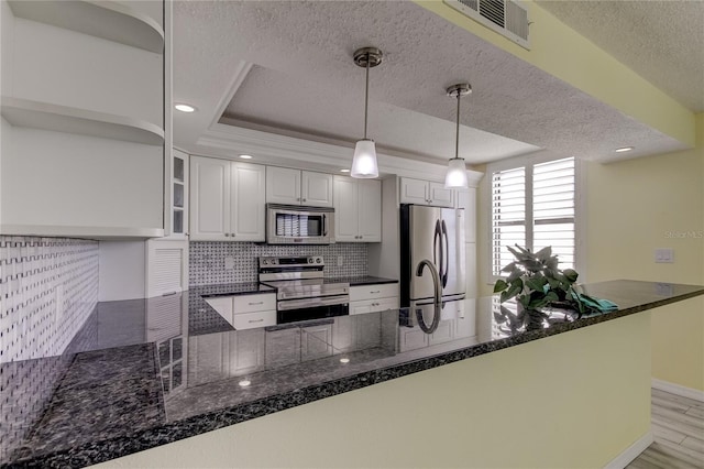 kitchen featuring kitchen peninsula, white cabinetry, pendant lighting, and stainless steel appliances