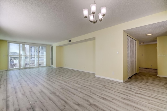 unfurnished living room featuring light hardwood / wood-style floors, a textured ceiling, and a chandelier