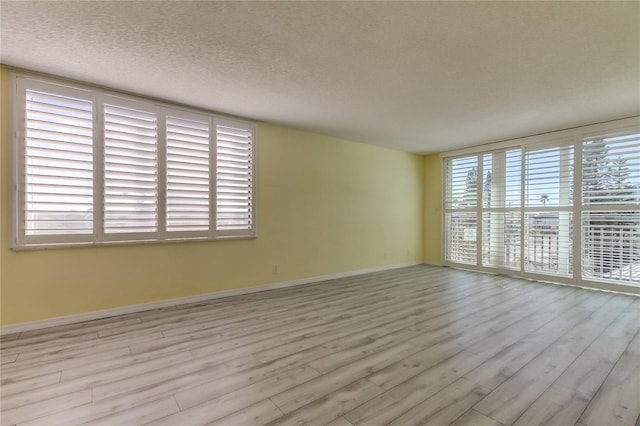 spare room with light wood-type flooring and a textured ceiling