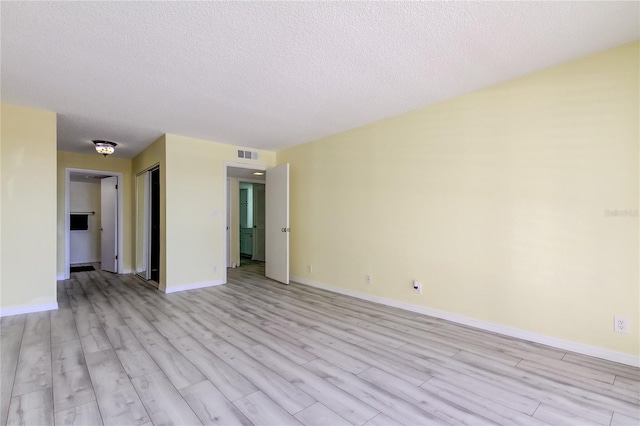 empty room featuring a textured ceiling and light hardwood / wood-style flooring