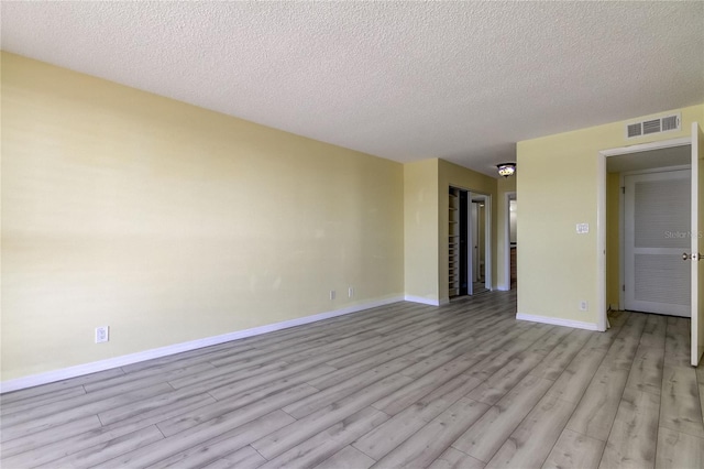 empty room with light hardwood / wood-style floors and a textured ceiling