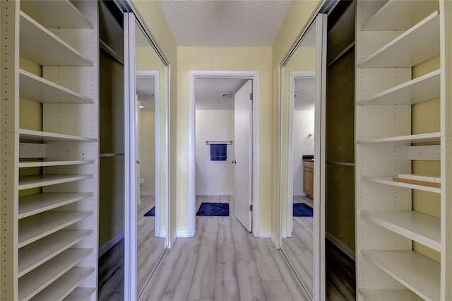 walk in closet with light hardwood / wood-style flooring