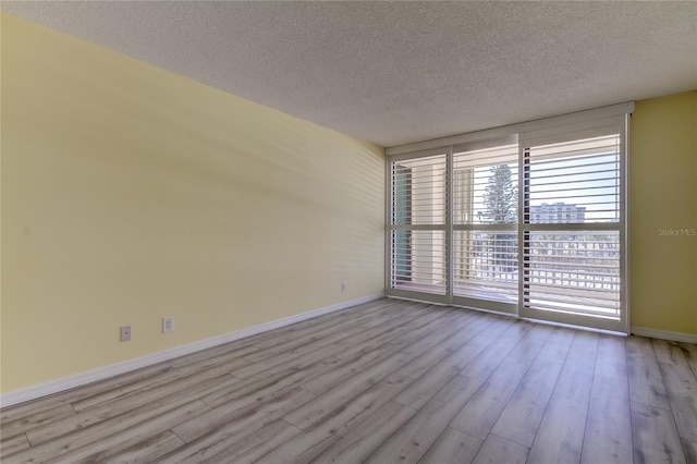 unfurnished room featuring a textured ceiling and light hardwood / wood-style flooring