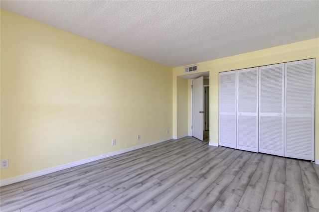 unfurnished bedroom with a closet, light hardwood / wood-style flooring, and a textured ceiling