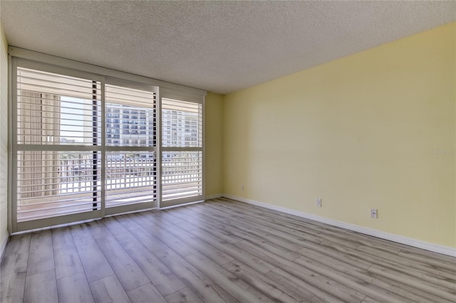 empty room with a textured ceiling and light wood-type flooring