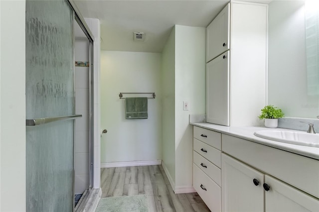 bathroom featuring hardwood / wood-style floors, vanity, and a shower with shower door