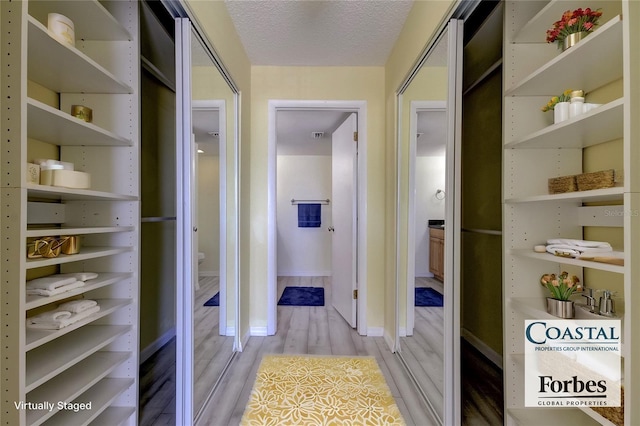 hallway with light hardwood / wood-style floors and a textured ceiling