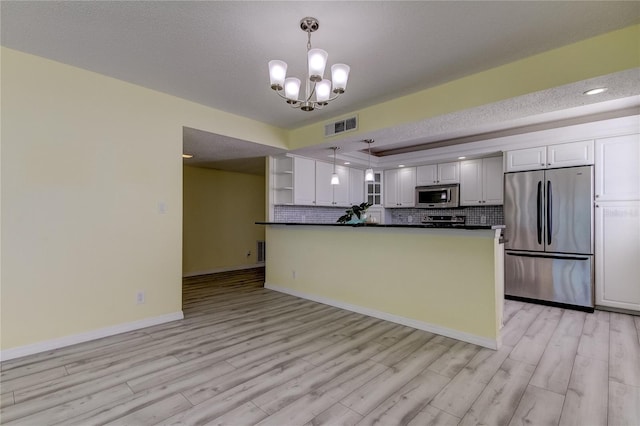 kitchen featuring light wood finished floors, dark countertops, visible vents, decorative backsplash, and appliances with stainless steel finishes