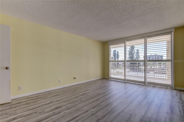 empty room with baseboards, floor to ceiling windows, and wood finished floors