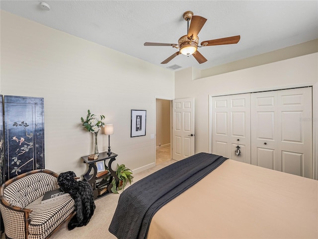 bedroom featuring ceiling fan, a closet, light carpet, and a textured ceiling