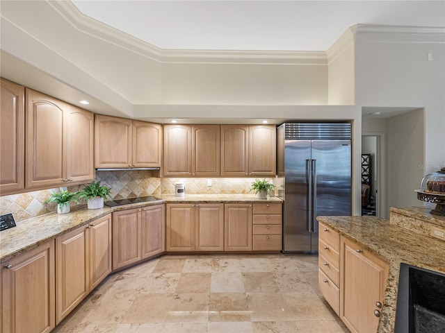 kitchen with backsplash, light stone counters, black electric cooktop, crown molding, and stainless steel built in fridge