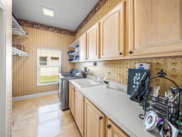 clothes washing area featuring washing machine and dryer, sink, light tile patterned floors, and cabinets