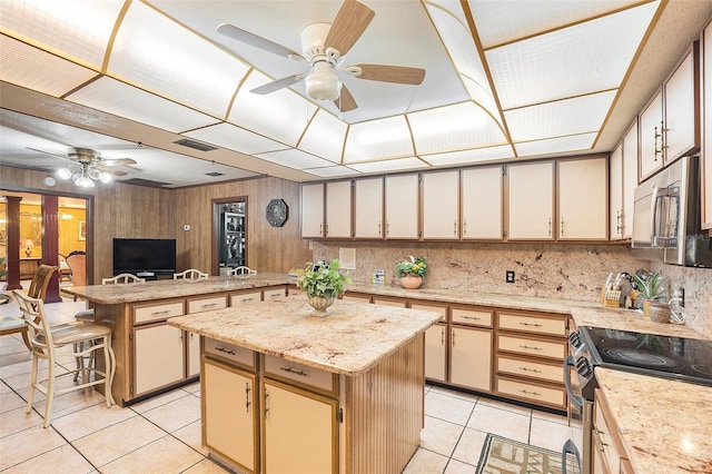 kitchen featuring appliances with stainless steel finishes, a kitchen breakfast bar, a center island, light tile patterned floors, and kitchen peninsula