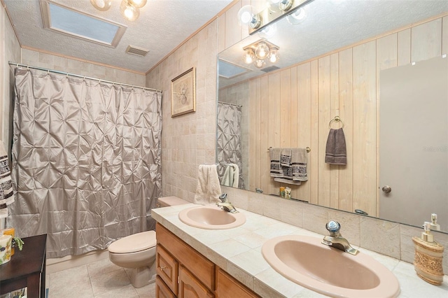 bathroom featuring vanity, walk in shower, toilet, tile patterned floors, and a textured ceiling