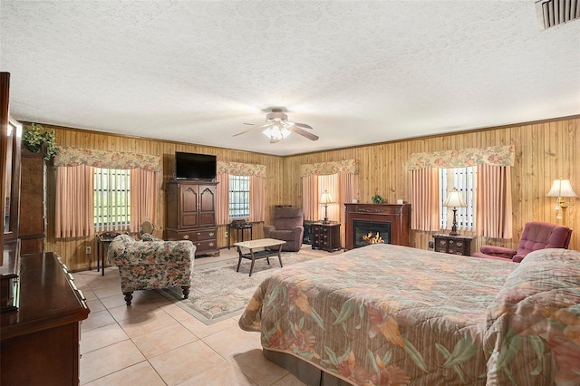 bedroom with wooden walls, light tile patterned floors, and a textured ceiling