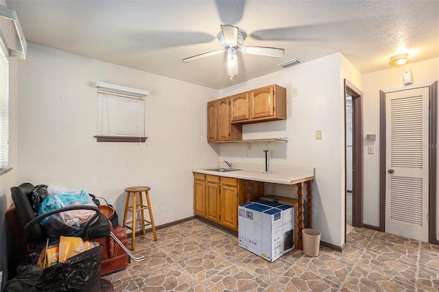 kitchen featuring sink, a textured ceiling, and ceiling fan