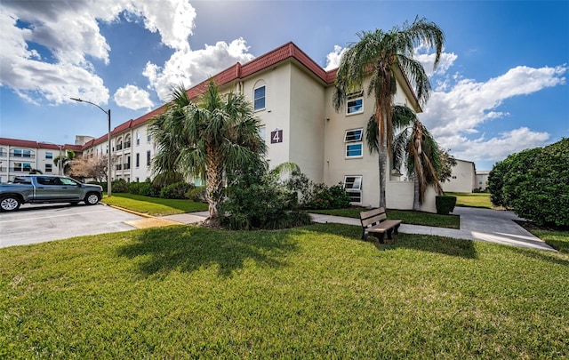 2700 Bayshore Blvd Unit 4304, Dunedin, FL 34698 - view of front of property featuring stucco siding, a front lawn, and uncovered parking
