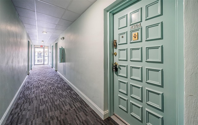 hallway with a drop ceiling and dark carpet