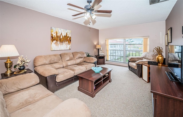 living room with ceiling fan, a textured ceiling, and light carpet