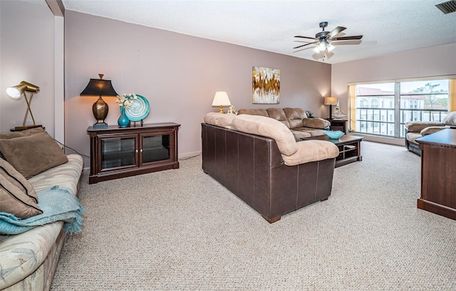 living room with ceiling fan, light colored carpet, and a textured ceiling