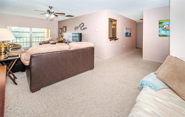 carpeted living room featuring ceiling fan and a textured ceiling