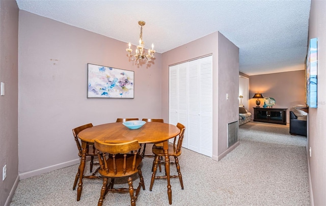 dining space with a chandelier, light colored carpet, and a textured ceiling